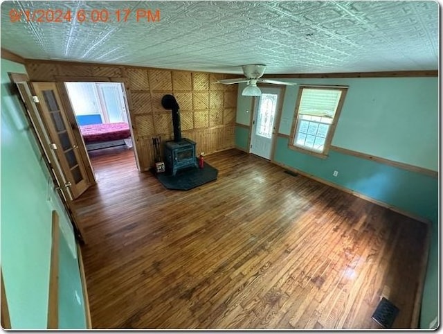 unfurnished living room with hardwood / wood-style floors, a wood stove, and ceiling fan