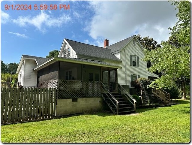 back of house featuring a sunroom and a lawn