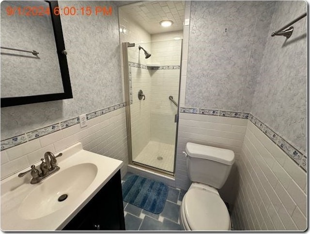 bathroom with tile patterned floors, a shower with door, vanity, and toilet