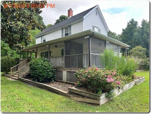 view of side of property featuring a sunroom and a lawn