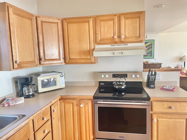 5108 Wildcat Ln, Chincoteague, VA 23336 - kitchen with electric range, under cabinet range hood, light countertops, white microwave, and light brown cabinetry