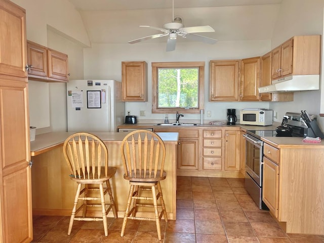 5108 Wildcat Ln, Chincoteague, VA 23336 - kitchen featuring white appliances, under cabinet range hood, light brown cabinets, vaulted ceiling, and a breakfast bar