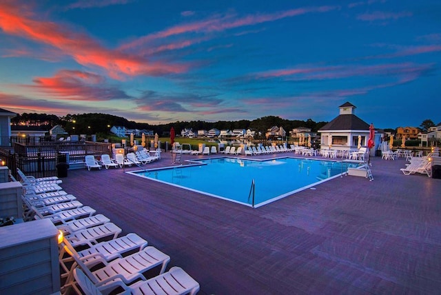 pool at dusk with a community pool, fence, and a patio area