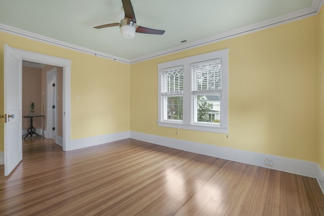 unfurnished room featuring ornamental molding, baseboards, and wood finished floors