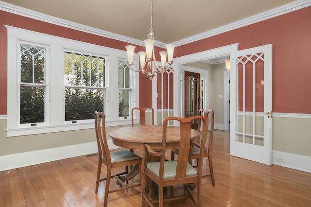 dining room with a notable chandelier, baseboards, crown molding, and wood finished floors