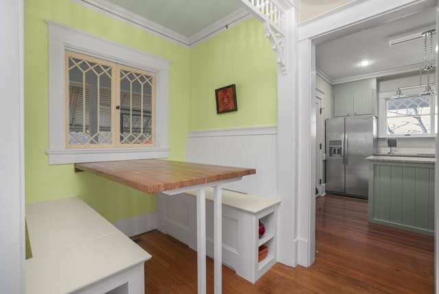 kitchen with dark wood finished floors, wainscoting, crown molding, and stainless steel fridge with ice dispenser