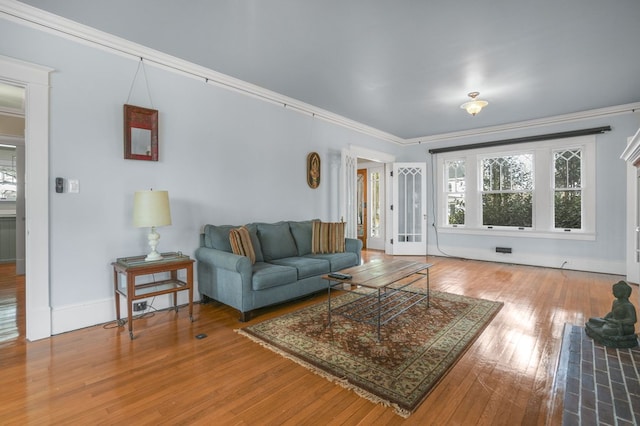 living room featuring baseboards, ornamental molding, and wood finished floors