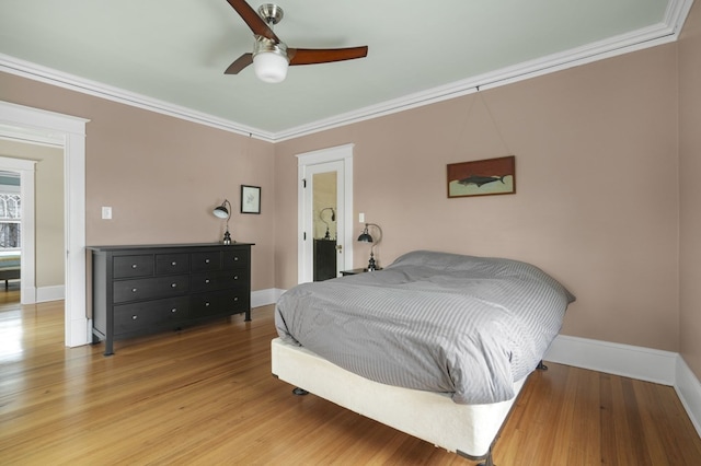 bedroom with crown molding, baseboards, and wood finished floors