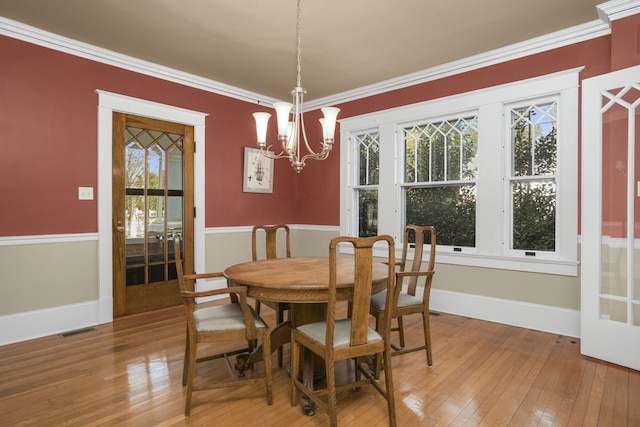 dining room with ornamental molding, visible vents, baseboards, and wood finished floors