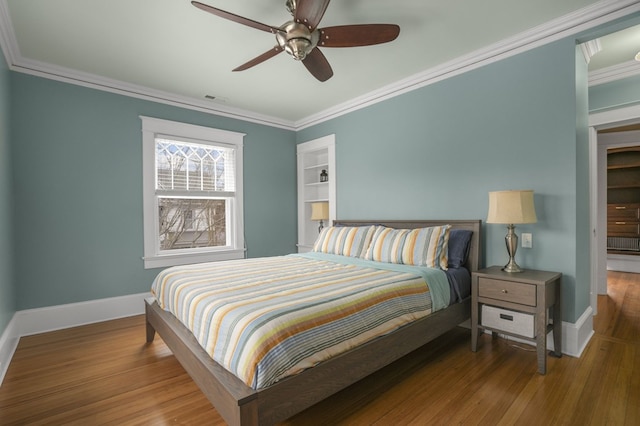 bedroom with baseboards, wood finished floors, and ornamental molding