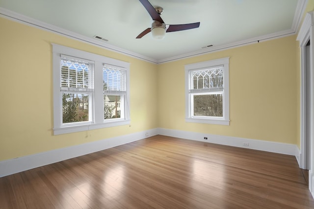 spare room with ornamental molding, a wealth of natural light, visible vents, and wood finished floors