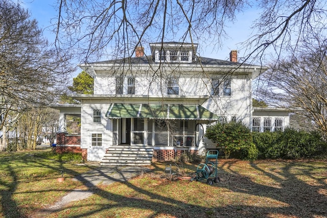 traditional style home with a chimney and a front lawn