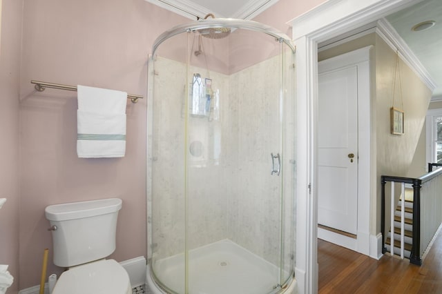 full bath featuring ornamental molding, wood finished floors, a shower stall, and toilet