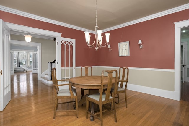 dining room featuring baseboards, stairway, ornamental molding, wood finished floors, and a notable chandelier