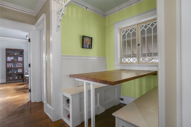 dining space featuring ornamental molding, breakfast area, dark wood-type flooring, and wainscoting