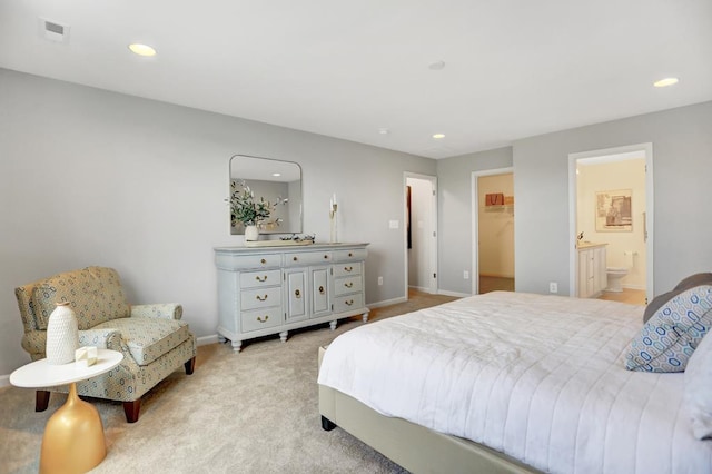 bedroom featuring ensuite bath, a walk in closet, a closet, and light colored carpet