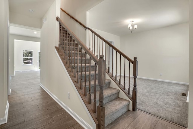 stairway with carpet flooring and an inviting chandelier