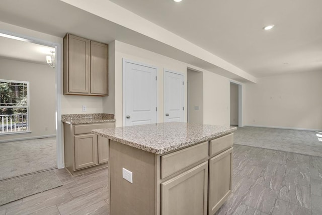 kitchen with light brown cabinetry, a center island, and light stone counters