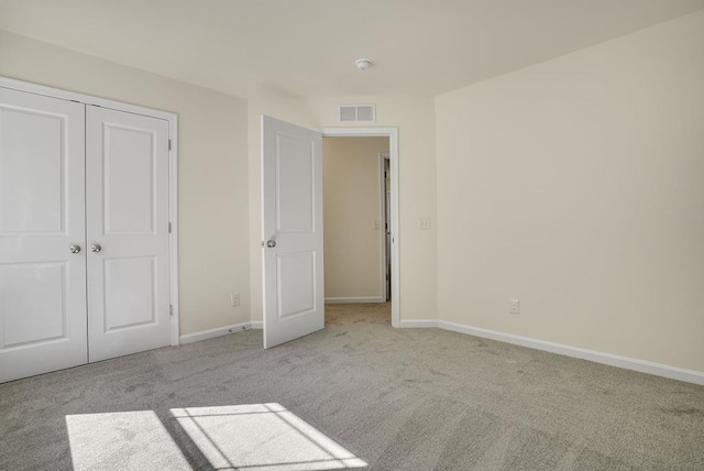 unfurnished bedroom featuring light carpet and a closet