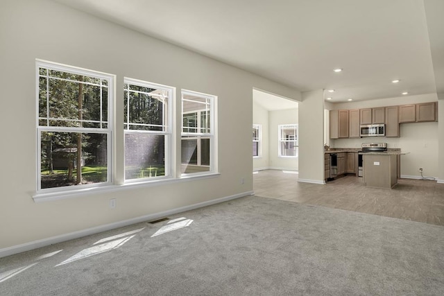 unfurnished living room with a wealth of natural light and light carpet