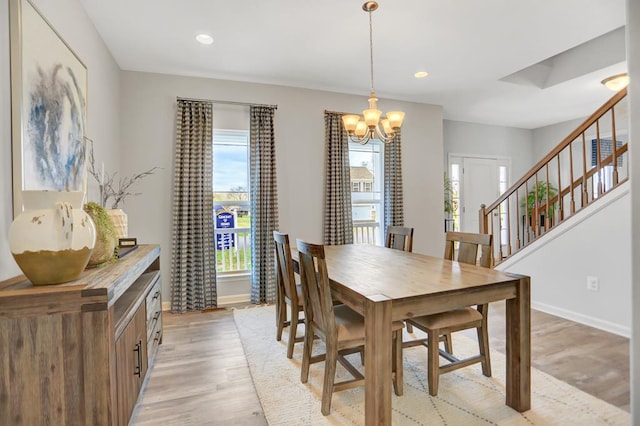 dining area with light hardwood / wood-style flooring and an inviting chandelier