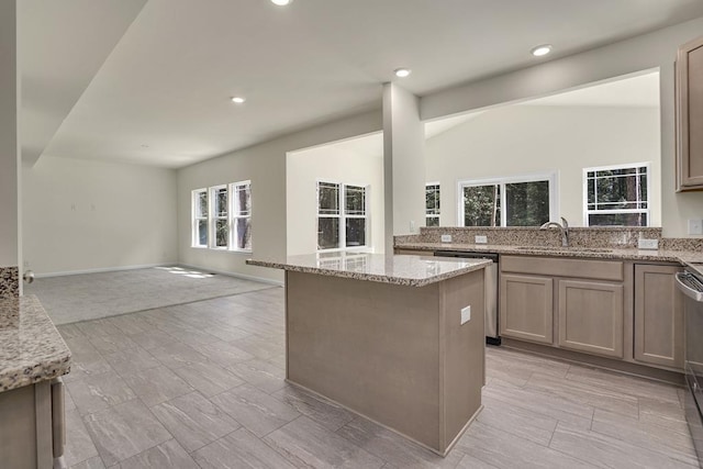 kitchen with dishwasher, light stone counters, sink, and a kitchen island