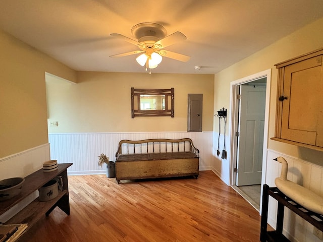 bedroom featuring electric panel, wainscoting, ceiling fan, and wood finished floors