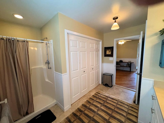 bathroom with a shower with curtain, a ceiling fan, and wainscoting