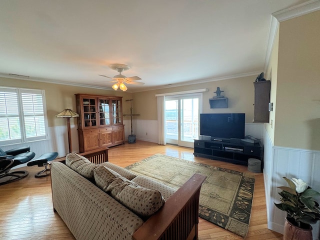 living room featuring ornamental molding, light wood finished floors, and wainscoting