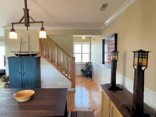 dining room featuring stairway, visible vents, light wood-style floors, and ornamental molding