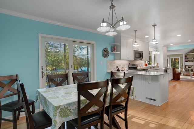 dining space with light hardwood / wood-style flooring, an inviting chandelier, and ornamental molding