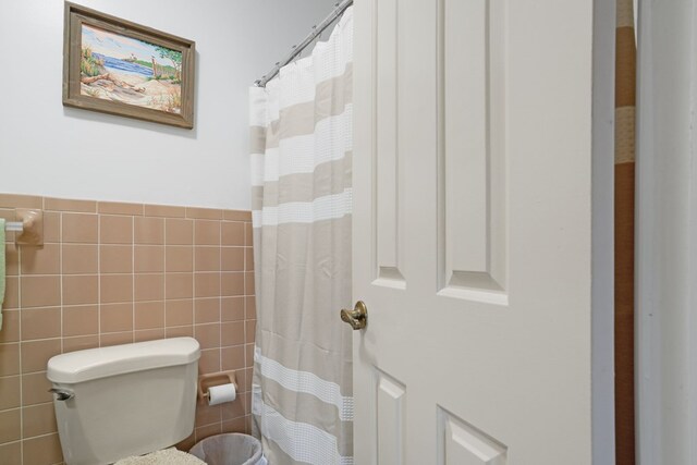 bathroom featuring toilet and tile walls