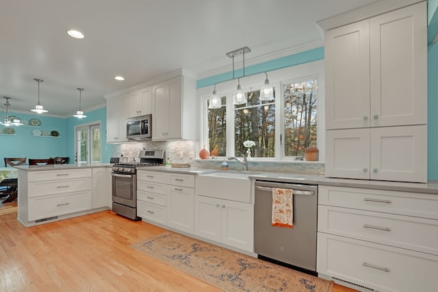 10388 Highland Ct, Exmore, VA 23350 - kitchen featuring tasteful backsplash, crown molding, light wood-style flooring, appliances with stainless steel finishes, and a peninsula