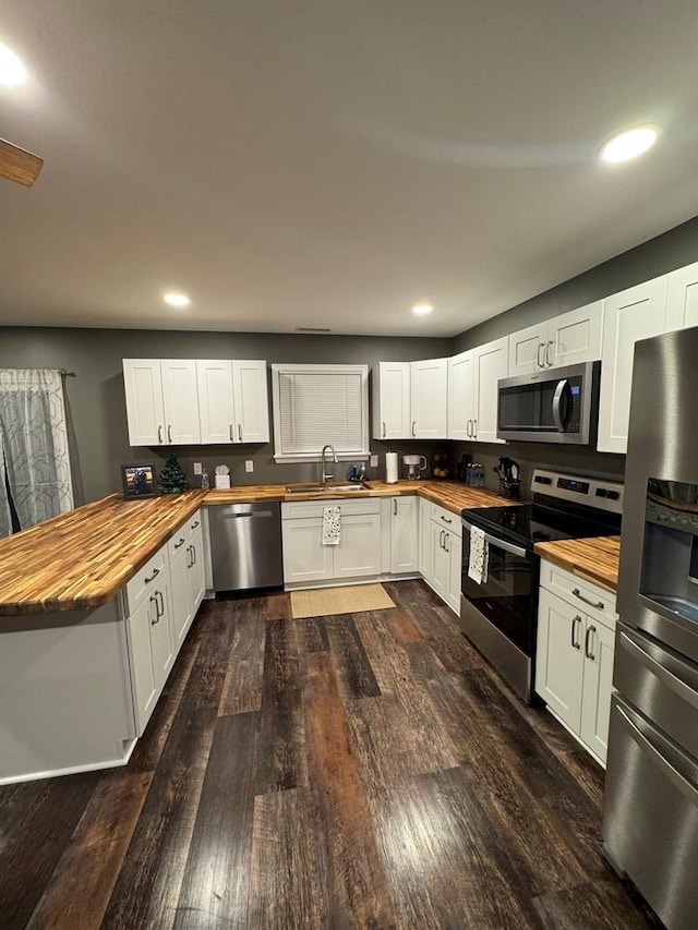 kitchen featuring appliances with stainless steel finishes, butcher block countertops, white cabinetry, and sink