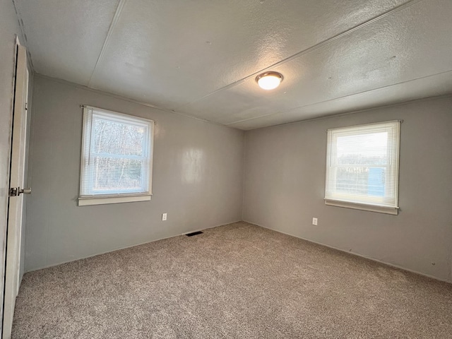 empty room with light carpet and a textured ceiling