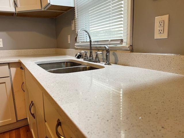 kitchen featuring light stone counters, sink, and wood-type flooring