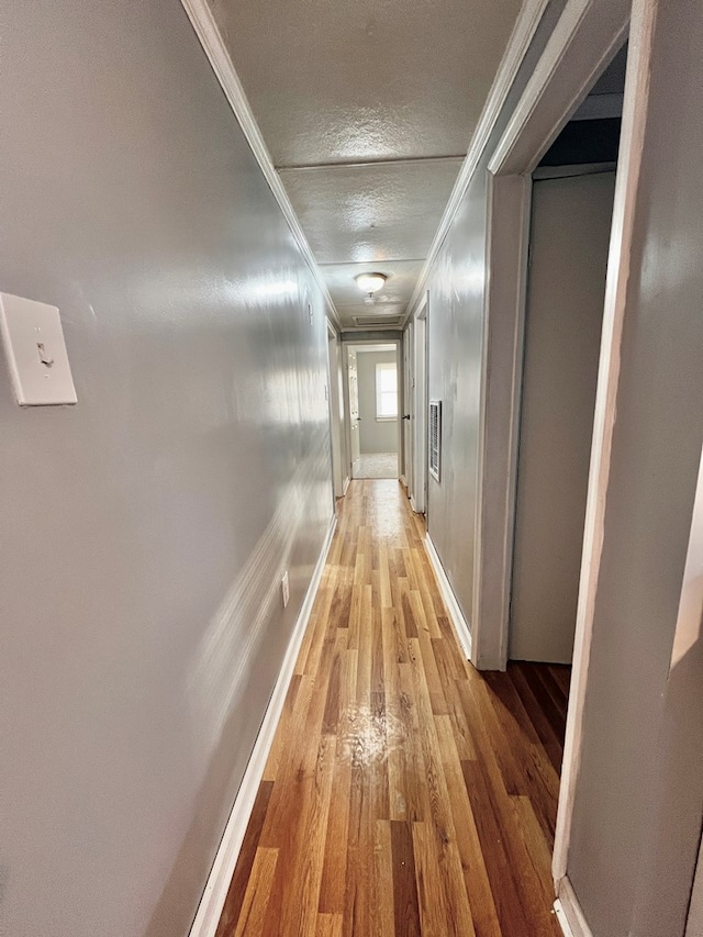 hall featuring ornamental molding, hardwood / wood-style floors, and a textured ceiling