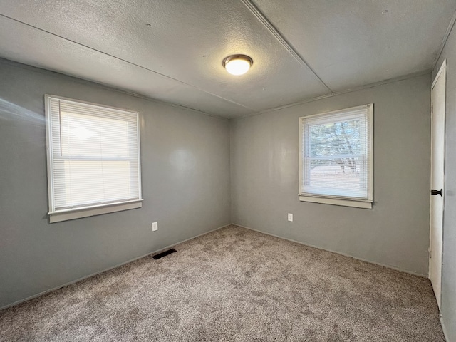 spare room featuring light carpet and a textured ceiling