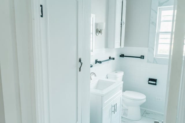 bathroom with vanity, toilet, and tile walls