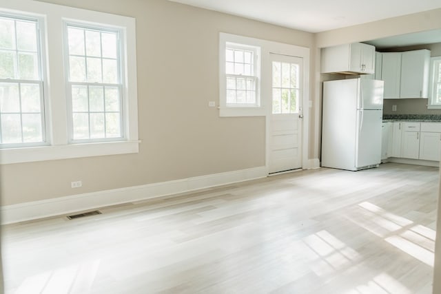 kitchen featuring light hardwood / wood-style floors, white refrigerator, white cabinetry, and a wealth of natural light