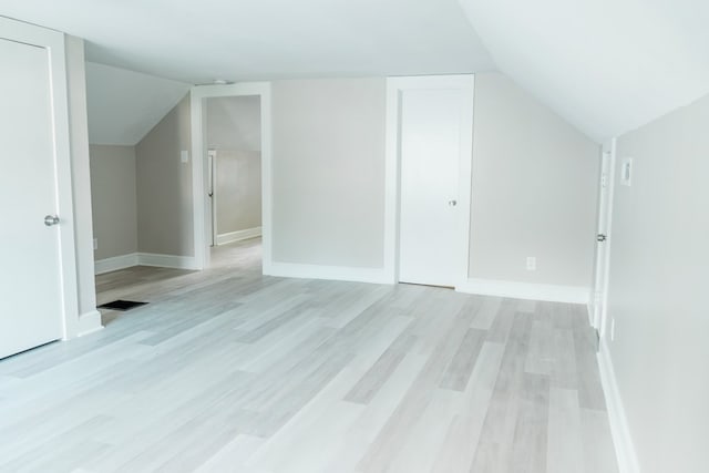 additional living space featuring light wood-type flooring and lofted ceiling