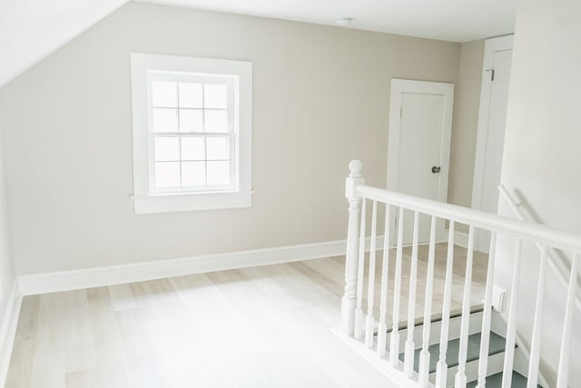 corridor with vaulted ceiling and hardwood / wood-style flooring