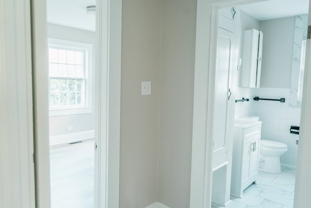 bathroom with vanity, tile walls, and toilet