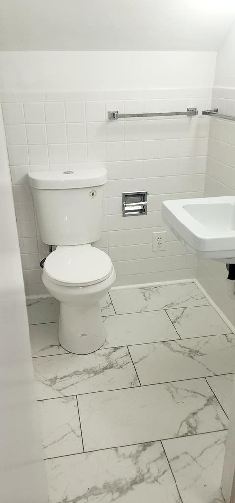 bathroom with tile walls and toilet