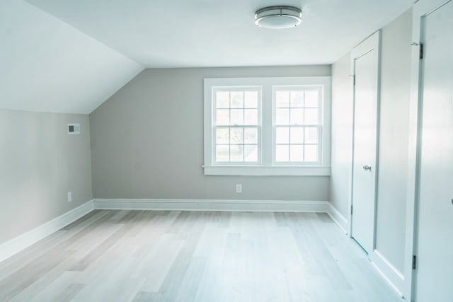 additional living space featuring light wood-type flooring and vaulted ceiling