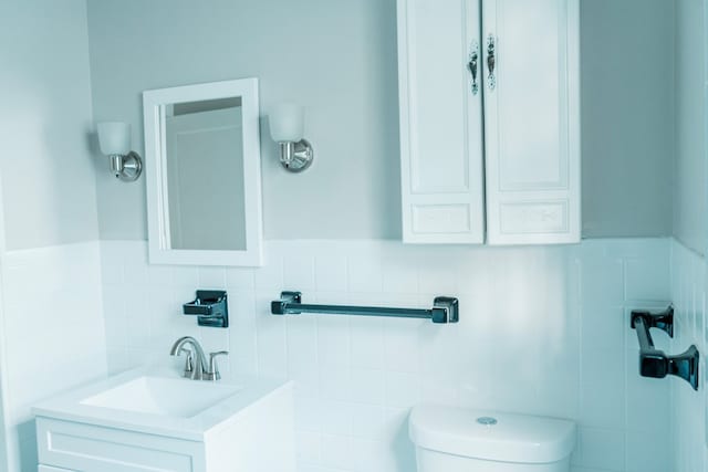 bathroom featuring vanity, tile walls, and toilet