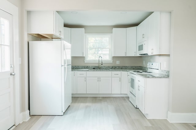 kitchen featuring white cabinetry, light stone countertops, white appliances, and sink