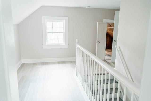 corridor featuring light hardwood / wood-style flooring and lofted ceiling