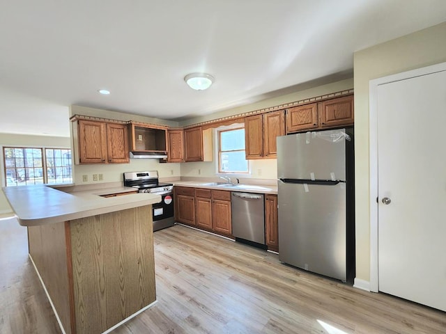 kitchen with kitchen peninsula, plenty of natural light, extractor fan, and appliances with stainless steel finishes