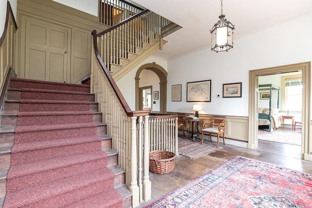 staircase featuring a chandelier, wood-type flooring, and ornamental molding